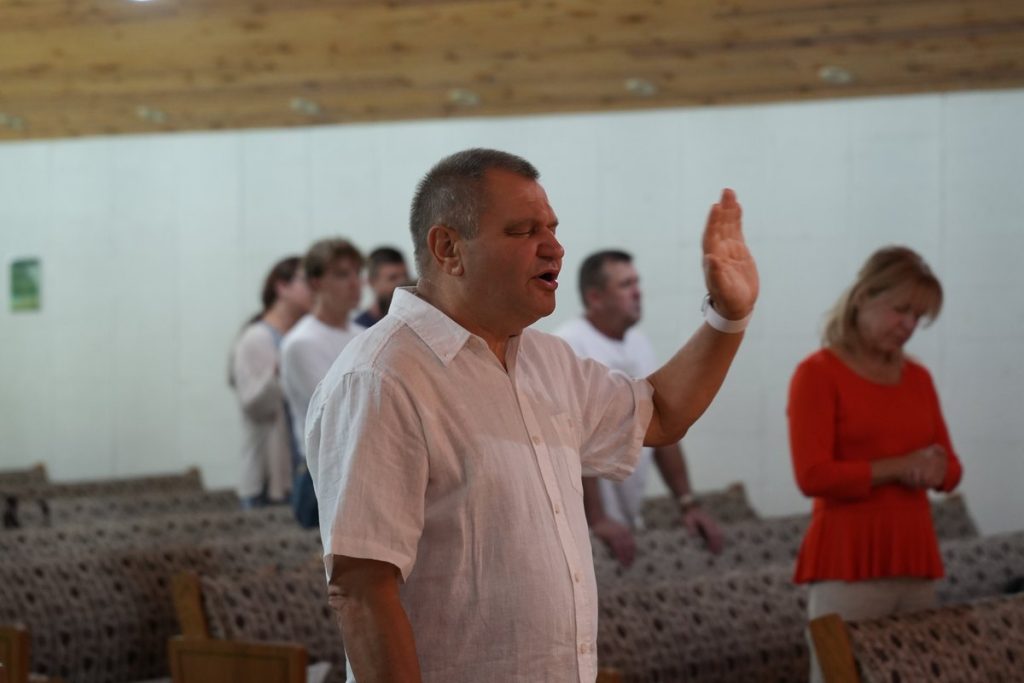 A man praying with his hand raised during a church prayer gathering